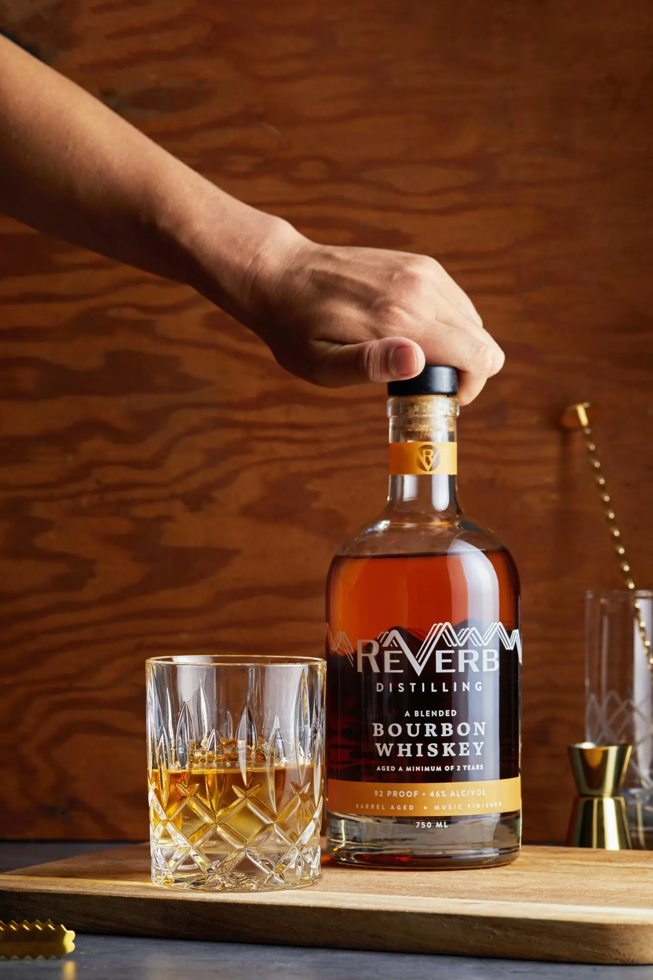 A hand placing a bottle of ReVerb Bourbon