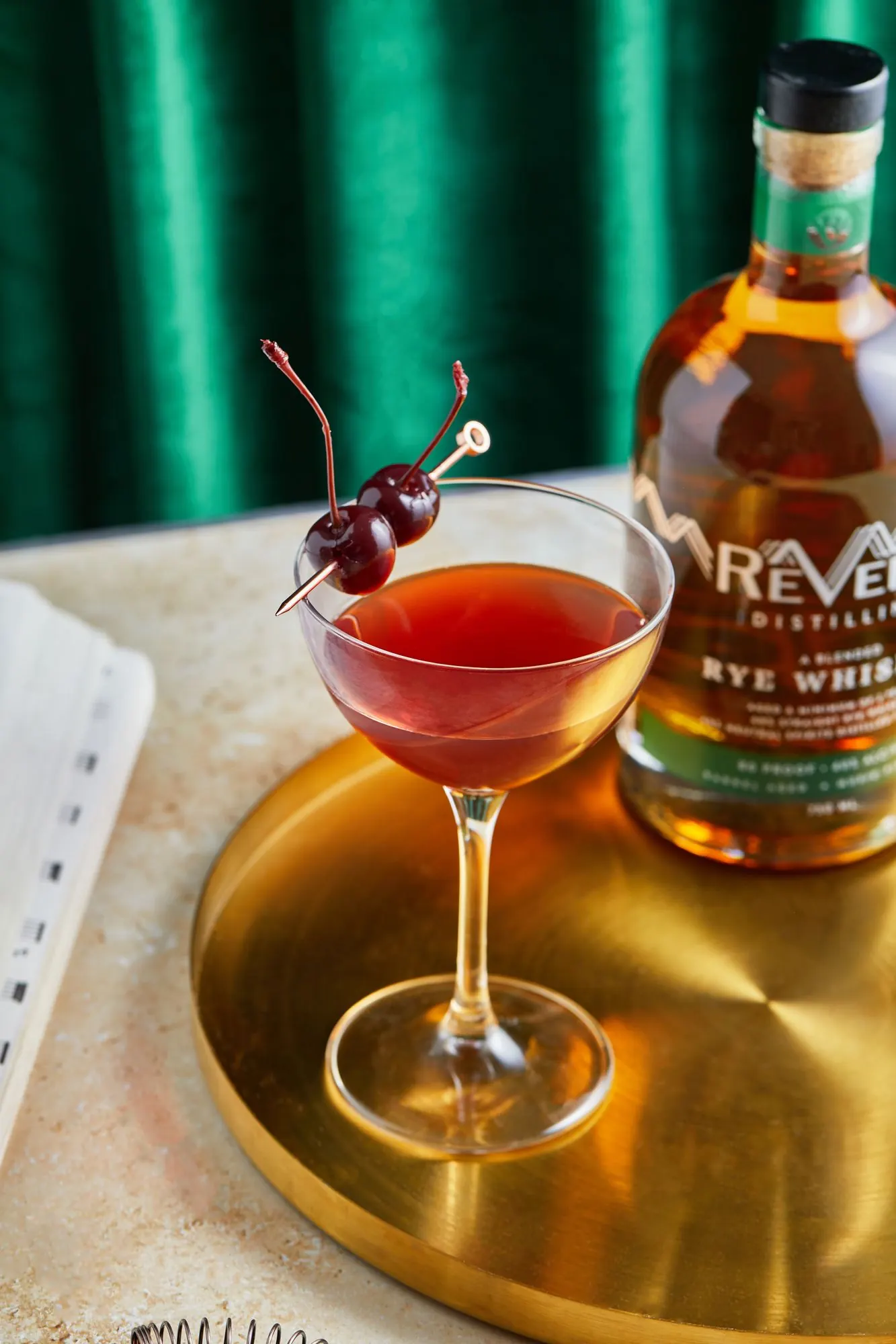 A rye Manhattan beside ReVerb Rye